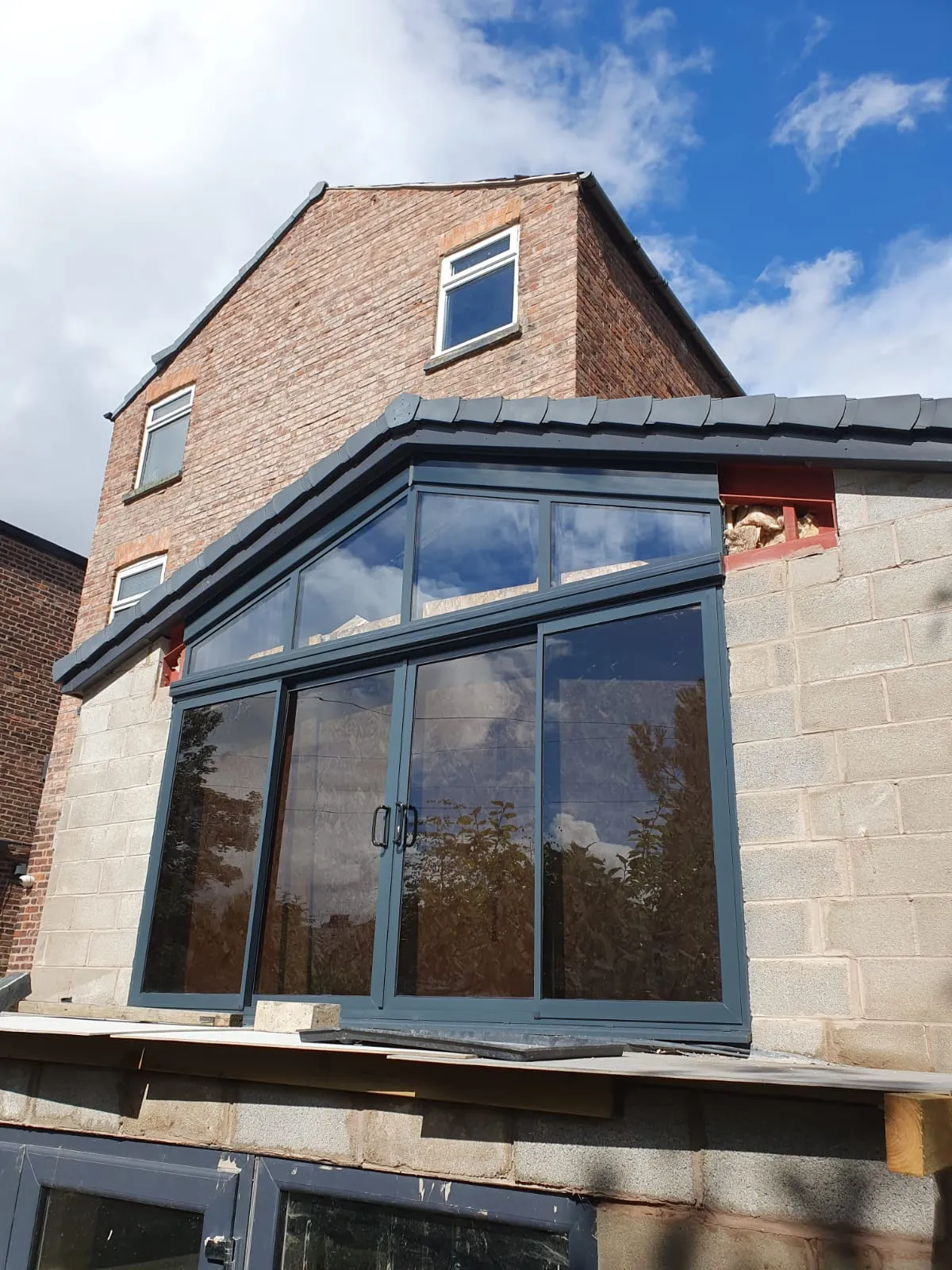 Grey aluminium corner bifold doors on a new-build rear extension in Manchester