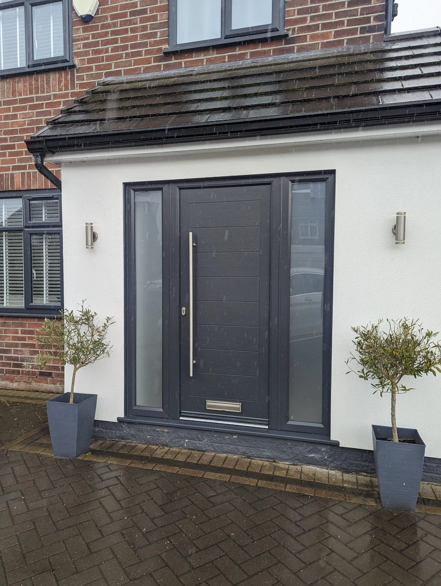 Anthracite composite front door with long bar handle and glazed side panels