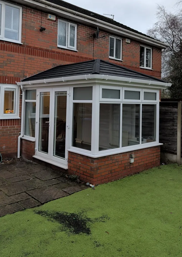 White PVC conservatory with a tiled roof on a red brick semi in Manchester
