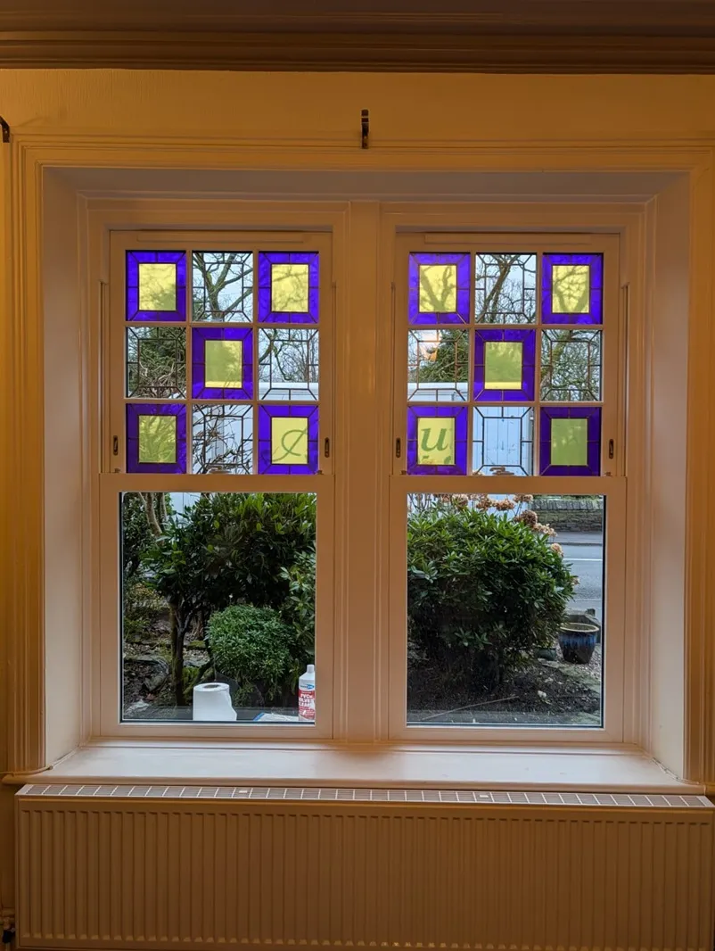 White PVC windows with decorative purple and yellow stained glass viewed from inside