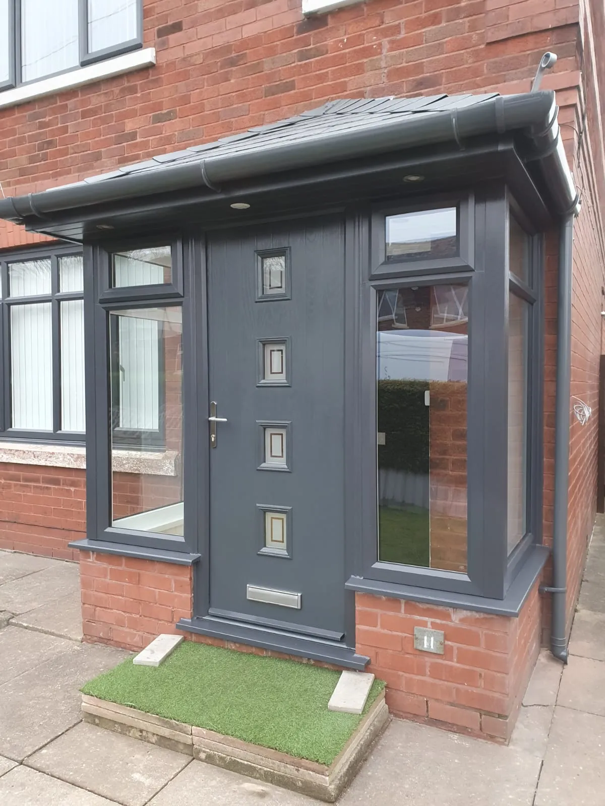 Anthracite grey composite front door with square glazing in a matching porch