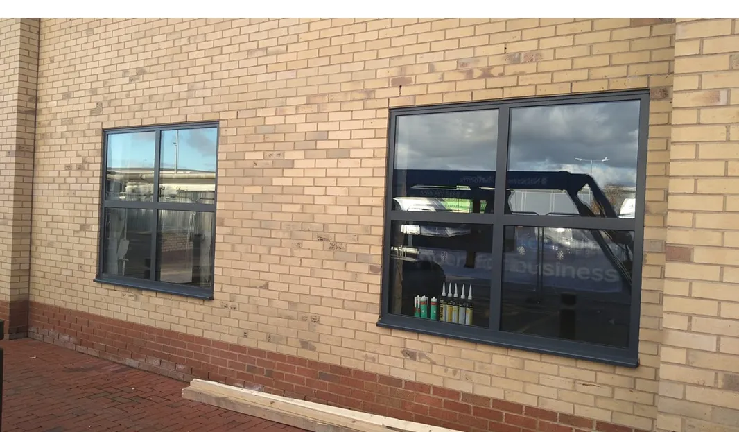 Grey aluminium commercial windows during installation on a new-build unit