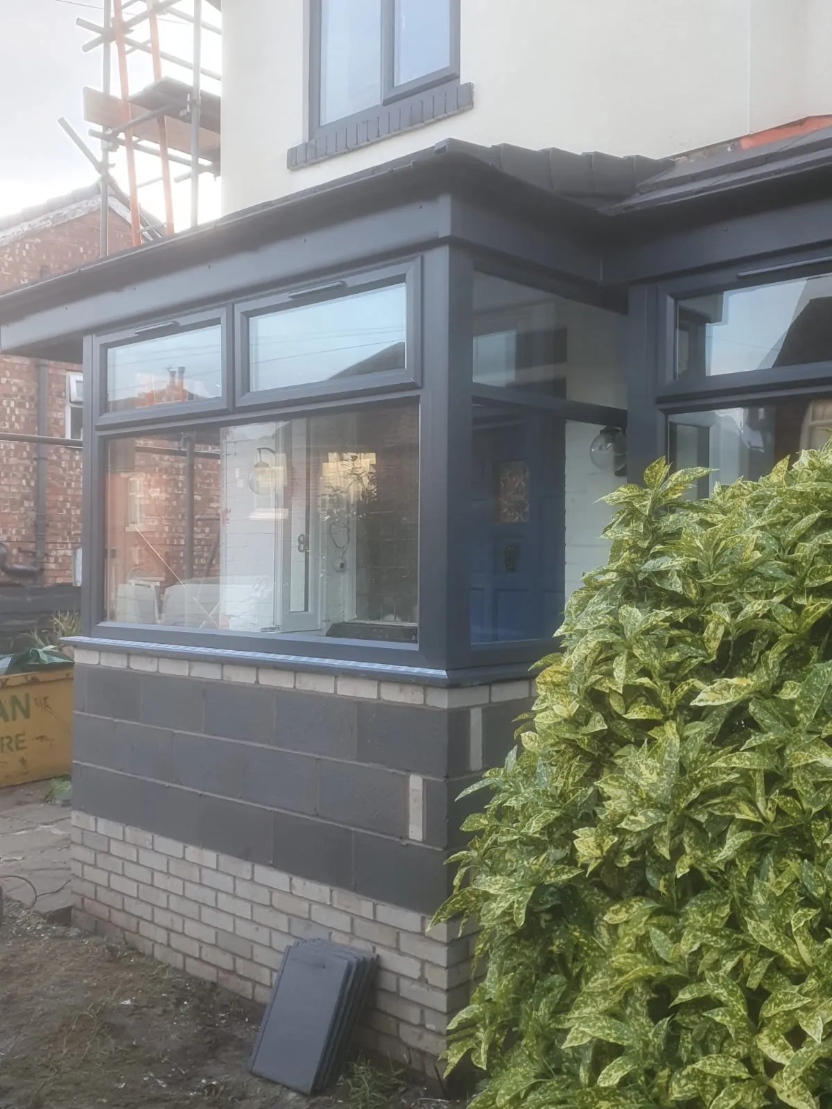 Grey aluminium porch extension with large glazed panels on a rendered home