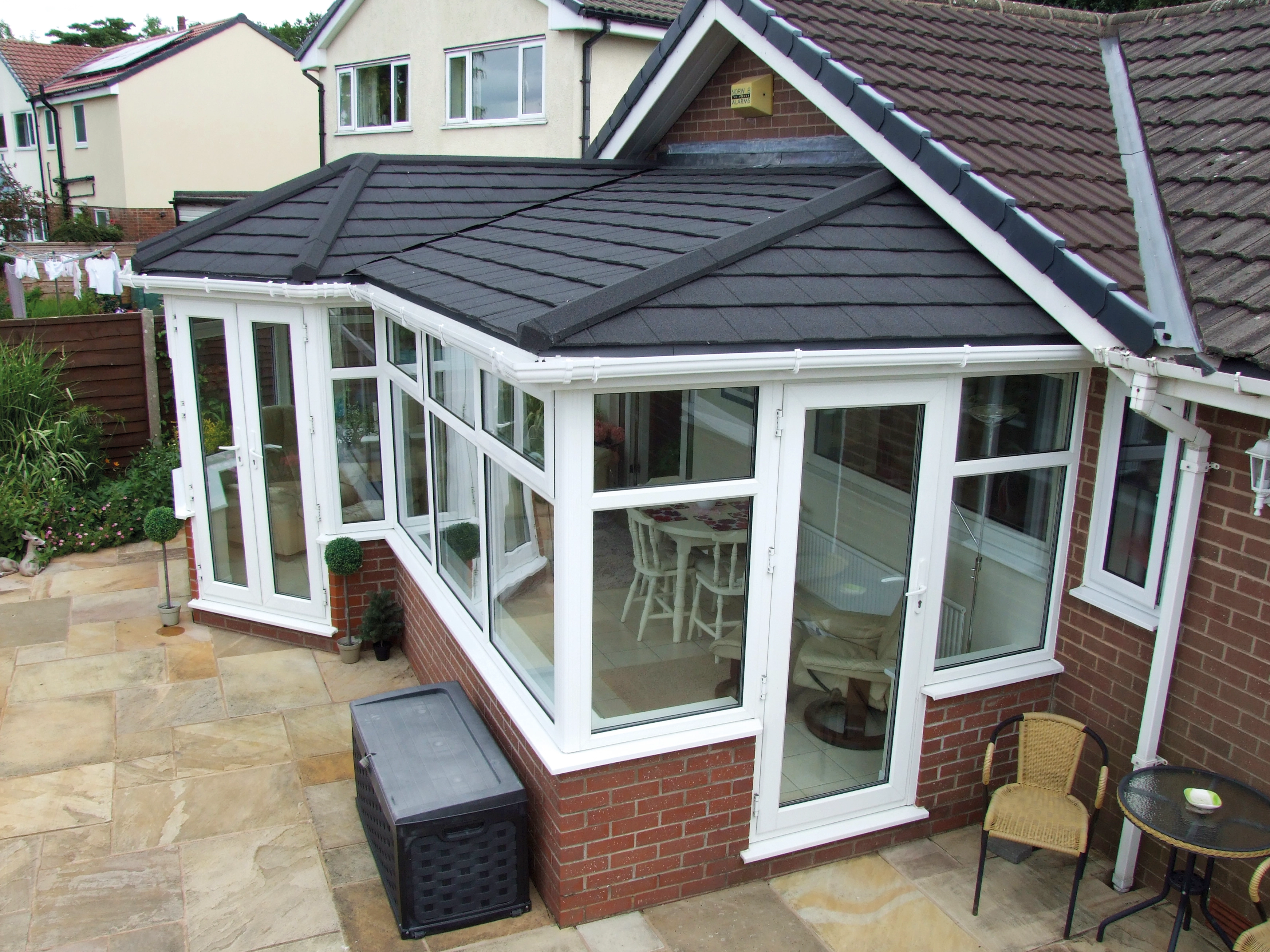 White PVC T-shaped conservatory with tiled roof and patio doors on a bungalow