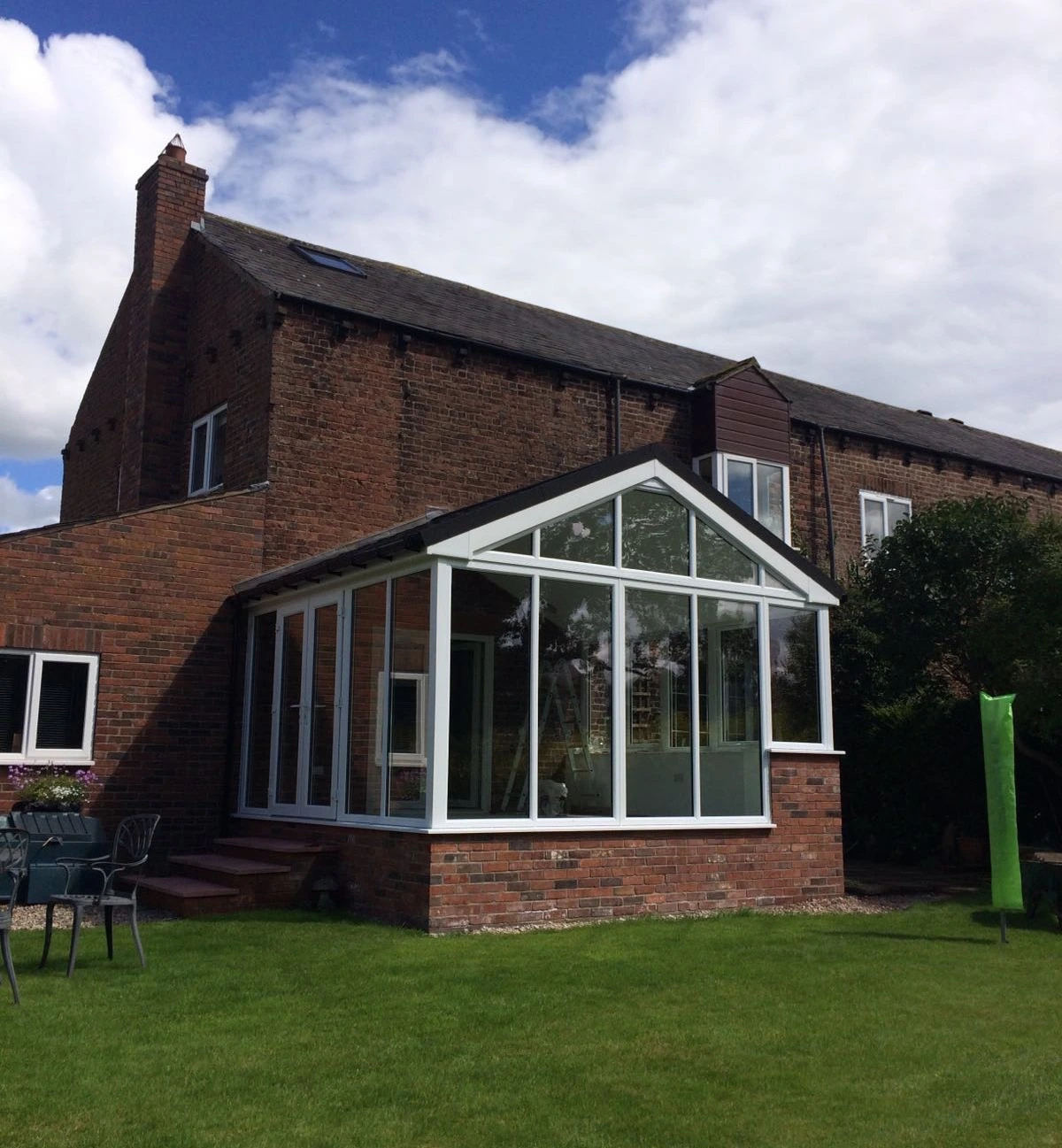 White PVC gable-front conservatory on a period brick farmhouse in Greater Manchester